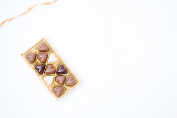 White background with a box of mixed belgium chocolate and a ribbon. Concept for any holiday greeting card, space for text, banner for designers.