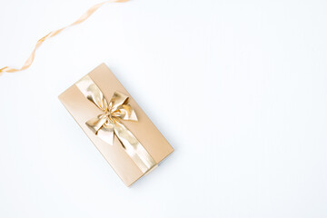 White background with a golden gift box and a ribbon. Concept for any holiday greeting card, space...