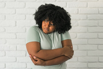 Portrait of depressed African American woman overthinking while standing brick wall at home