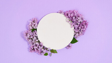 Natural branches and flowers of lilac near round white piece of paper. Сoming of spring. Lilac...