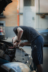 A young man removes the protective partition in the hood of a car.