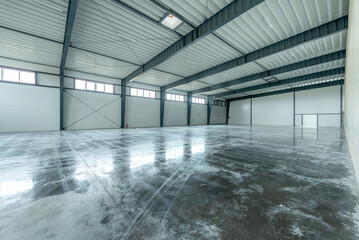 A large, open, industrial warehouse featuring polished concrete floors, steel beams, and bright lighting. This space is ideal for storage, logistics, manufacturing. Empty Industrial Warehouse