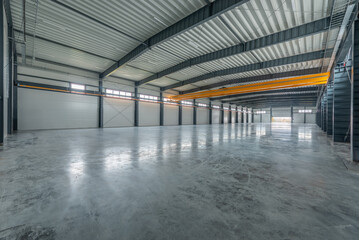 Large Industrial Warehouse With Modern Design and Empty Spacious Interior Layout. Yellow Crane In Background