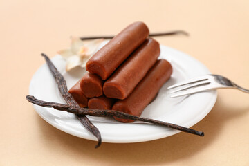 Plate with tasty chocolate glazed curd snacks with vanilla flavor on beige background