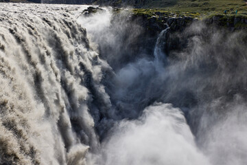 Dettifoss waterfall in Iceland.  Powerful cascade of water plunging into a canyon in Iceland. Mist and spray rising from the falls. Natural power and scenic beauty.