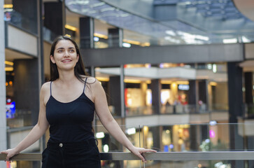 Mexican Young woman enjoys a moment in a busy shopping mall with modern architecture and vibrant atmosphere. A young woman stands confidently in a bustling shopping mall, Shopping concept