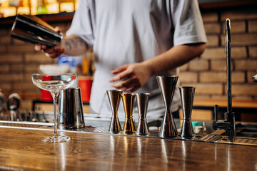 Bartender preparing a drink with jiggers and glassware in a stylish bar setting