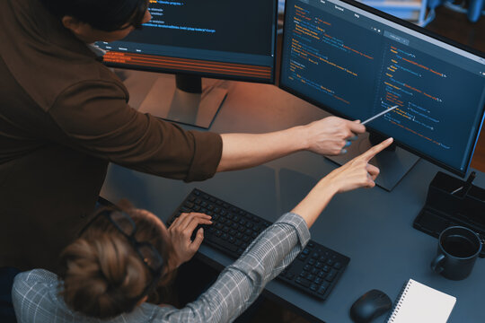 Top view of IT developers discussing with point to intelligent website development coder system running data online two screens information technology at neon light room at modern office. Infobahn.
