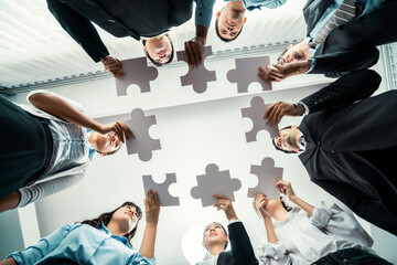 Multiethnic business people holding jigsaw pieces and merge them together as effective solution...