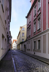 Narrow cobblestone street lined by tall houses on either side in a medieval town in southern Germany