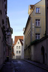 Narrow cobblestone street lined by tall houses on either side in a medieval town in southern Germany