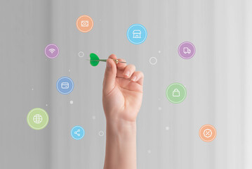 Hand holding a dart surrounded by various online shopping icons, symbolizing precision and strategy...