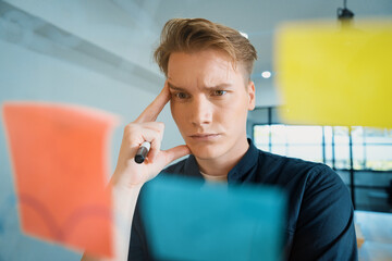 Professional caucasian businessman brainstorming marketing idea by using mind map and sticky notes on glass board at modern meeting room. Creative business and planing concept. Immaculate.