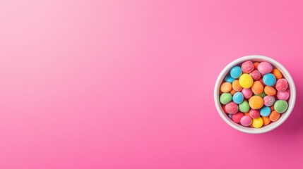 Obraz premium Colorful assorted candies in white bowl on vibrant pink background