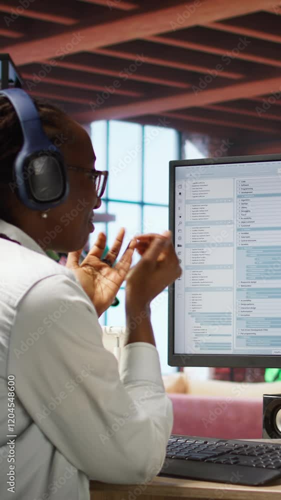 Poster vertical video excited programmer wearing headphones testing code on pc, clapping hands after seeing