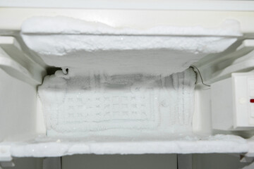empty freezer compartment of the refrigerator, iced up on the walls with ice creeping out, defrosting required,
