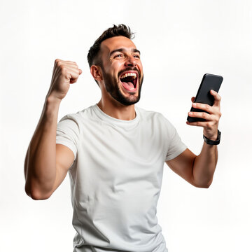 Happy young man celebrates online success with mobile phone. Excited male in casual clothing holds smartphone, shows winning gesture. Joyful expression on face. Studio shot against plain background.