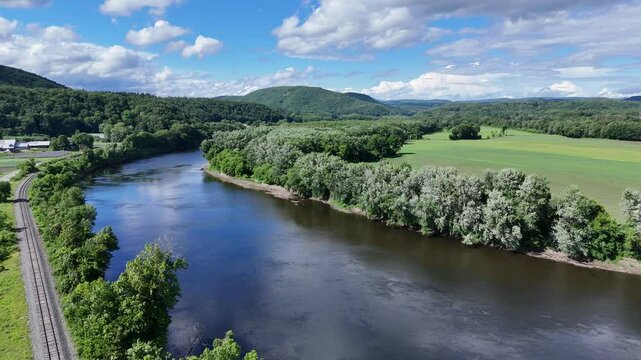 Aerial drone footage soaring over lush green farmland along the banks of the Connecticut River as it winds between southern Vermont and New Hampshire