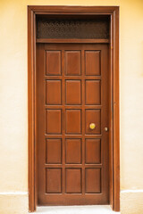 Wooden door with square panels and brass handle in brown frame