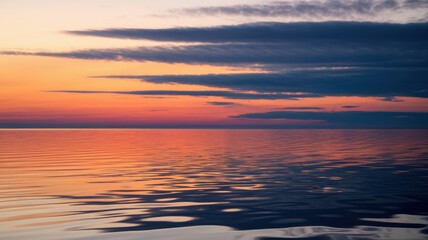 Fototapeta premium A serene sunset over calm waters, showcasing vibrant shades of orange, pink, and purple reflecting on the tranquil surface.