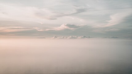 A serene landscape showcasing a soft blend of pastel colors in the sky and misty clouds, evoking tranquility and calmness.