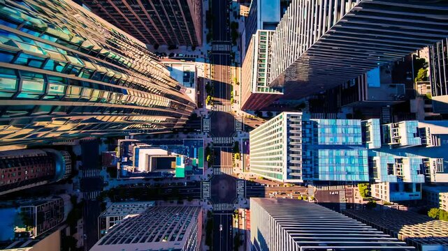 Aerial view of city skyscrapers and streets, showing the grid-like urban layout under bright sunlight.