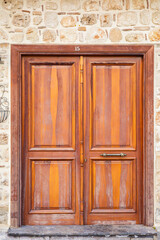 Obraz premium Rustic wooden door with metal handle on stone brick wall