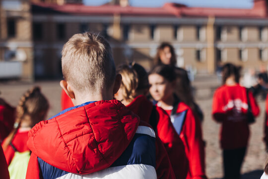 Group of school pupils and students on outdoor excursion tour in the city streets with guide, a docent with a tourist young visitors wearing red, school field trip, urban tour in the summer sunny day
