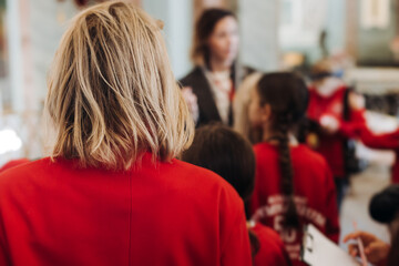 Group of kids children on excursion in a museum gallery, school pupils and students tour with guide, a docent with a tourists, young visitors wearing red, school field trip, art exhibition attendees
