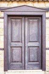 Rustic wooden door with stone wall background in sunlit outdoor setting