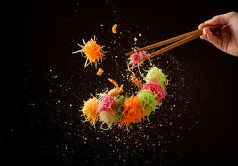 Close-up of chopsticks tossing the ingredients of Lo Hei ,Yu Sheng salad high in the air, creating a dynamic and colorful swirl, the energy and excitement of the tossing ceremony, Lunar New Year