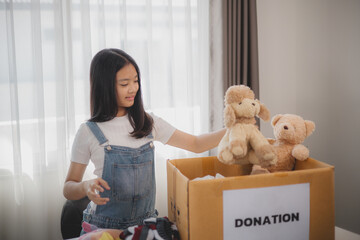 Recycling, Donation for poor, Asian girls packing objects at home, putting on stuff into donate box...