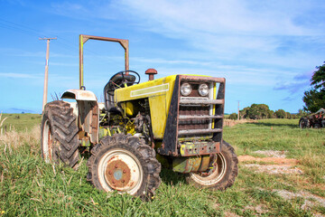 Yellow agricultural tractor outside on the farm in a rural area.