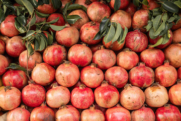 Fresh pomegranates with green leaves stacked for display