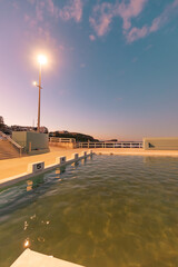 The Newcastle Ocean Baths at dusk with pink and purple fairy floss sky
