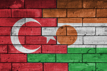 colourful painted big flag of turkey and flag of niger on a massive old brick wall background....