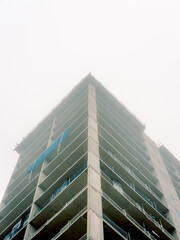 Fototapeta premium Modern office building under construction disappearing into the misty sky