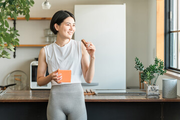 プロテインバー・栄養バーを食べるヨガウェア姿の若いアジア人女性
