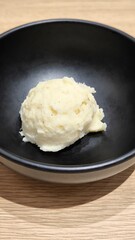 Mashed potatoes in a black cup on a wooden table