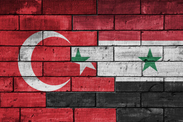 colourful painted big flag of turkey and flag of syria on a massive old brick wall background....
