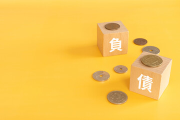 負債の文字が書かれたブロックとお金
