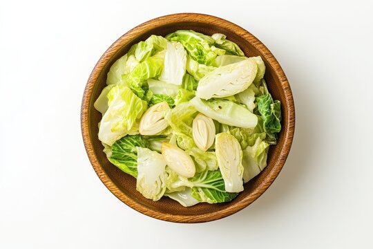 Indonesian dish tumis sawi putih saut&eacute;ed napa cabbage with garlic presented in a bowl against a white background viewed from above