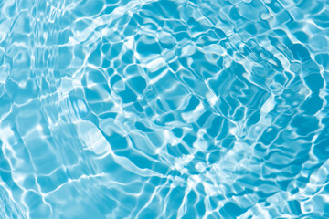 Blue water with ripples on the surface. Defocus blurred transparent blue colored clear calm water surface texture with splashes and bubbles. Water waves with shining pattern texture background.