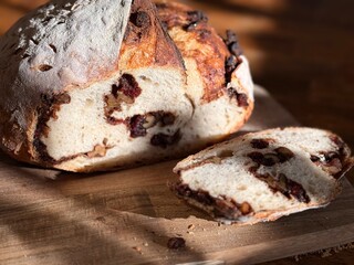 Sourdough bread featuring a rustic crust and a flavorful filling of cranberries and walnuts,...