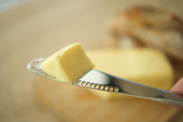 Delicious Butter Spread on a Knife with Freshly Baked Bread in the Background
