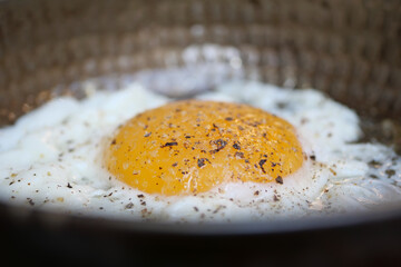 A closeup view of a delicious Fried Egg with vibrant Seasoning in a frying Pan