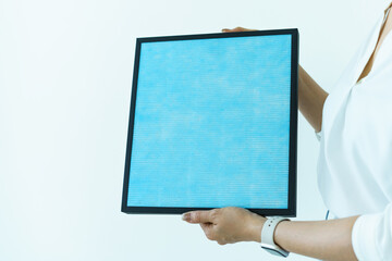 Asian woman showing the new carbon air purifier filter to camera close up. HEPA filter used in high efficiency air purifier system to purify the dirty or polluted air inside the house or vehicle.