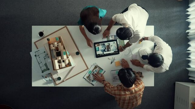 Time lapse of designer looking at model while discussing about building. Top view of architect engineer explaining idea while talking and writing blue print scattering at meeting table. Alimentation.