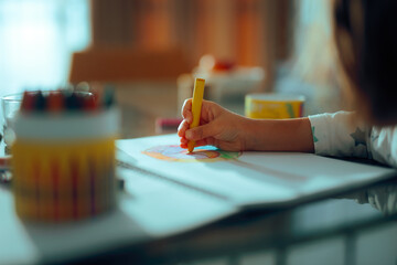 Girl Drawing at the Kitchen Table using Wax Crayons. Kid sketching something at home being inspired and creative 
