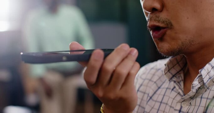 Speaking into smartphone, man using voice command feature in office setting